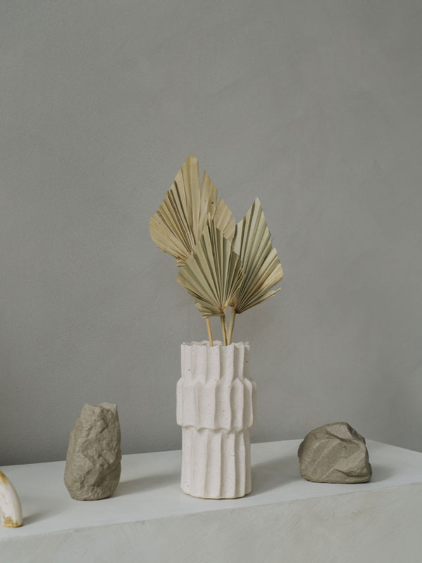 gedroogd palmblad in een schattige witte vaas met een zandachtige textuur